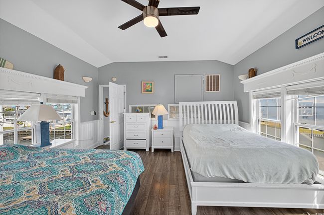 Bedroom featuring lofted ceiling, dark wood-style floors, a wainscoted wall, and a ceiling fan | Image 9