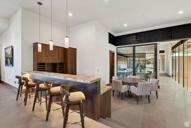 Kitchen featuring a kitchen bar, pendant lighting, recessed lighting, light countertops, and modern cabinets | Image 54