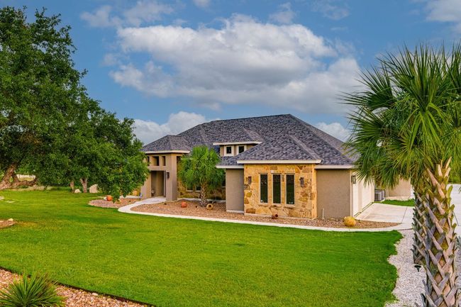View of front of house featuring stone siding, stucco siding, a front yard, an attached garage, and concrete driveway | Image 6