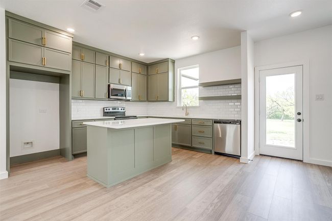 Kitchen featuring stainless steel appliances, visible vents, backsplash, and light wood-style flooring | Image 9