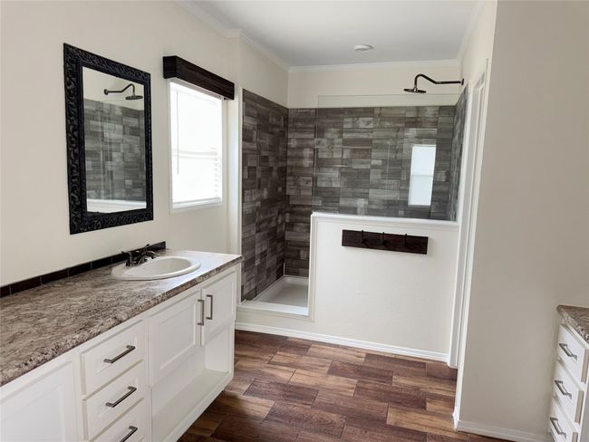 Bathroom featuring vanity, walk in shower, crown molding, and wood finished floors | Image 11