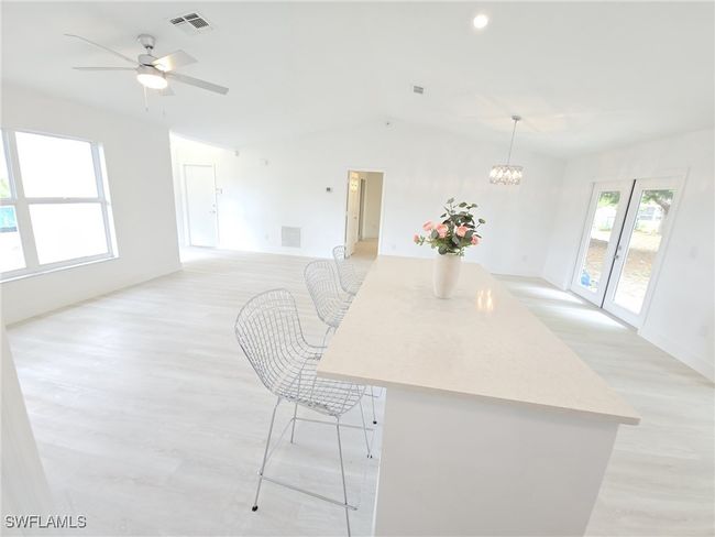 Kitchen featuring lofted ceiling, light wood finished floors, light countertops, ceiling fan, and a center island | Image 13