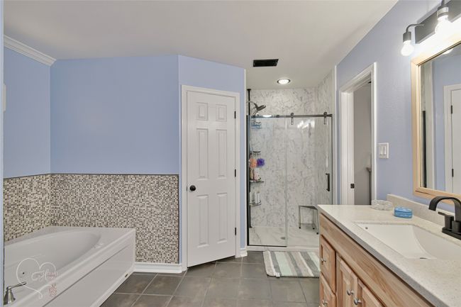 Full bath featuring tile patterned floors, vanity, a marble finish shower, and a bath | Image 26