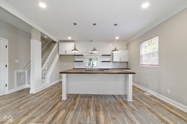 kitchen with butcher block counters, crown molding, light wood-type flooring, open shelves, and white cabinetry | Image 12