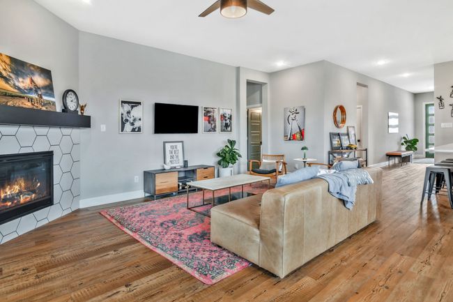 Living room with light wood-style floors, a ceiling fan, a tiled fireplace, and recessed lighting | Image 13