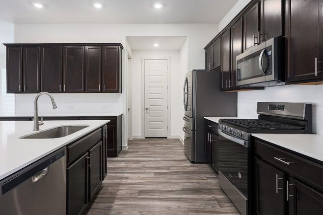 Kitchen with appliances with stainless steel finishes, recessed lighting, light countertops, light wood-style floors, and dark brown cabinetry | Image 9