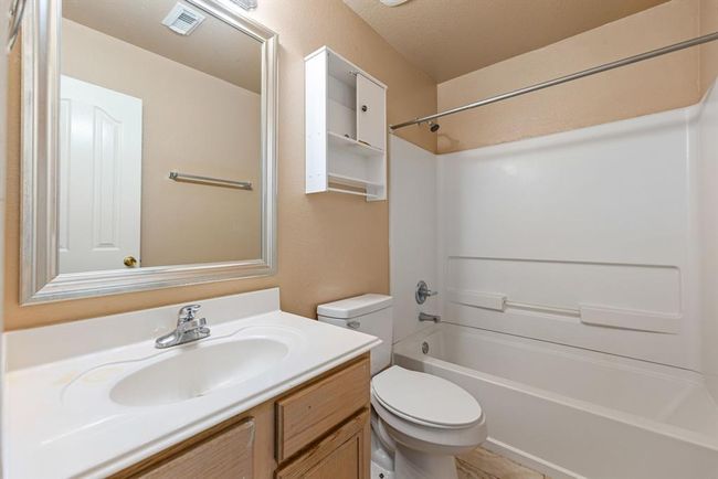 Charming and functional, this full bath includes a bright vanity area, neutral tones, and a tub/shower combo with built-in shelving perfect for guests or family use. | Image 17