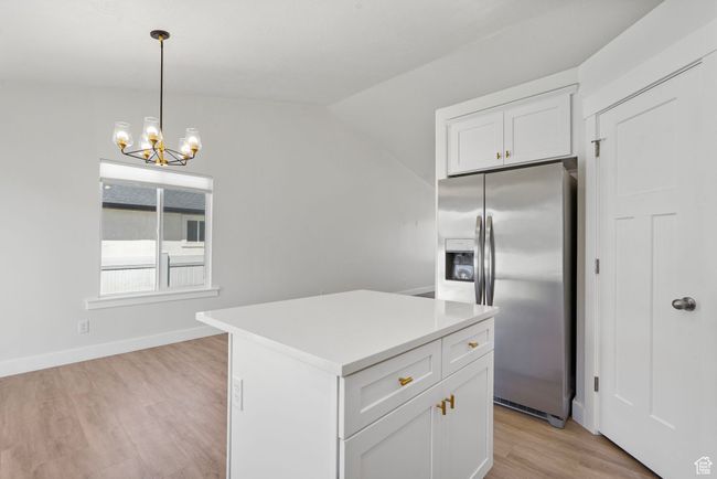 Kitchen with stainless steel fridge, light wood-style floors, white cabinets, a chandelier, and pendant lighting | Image 7