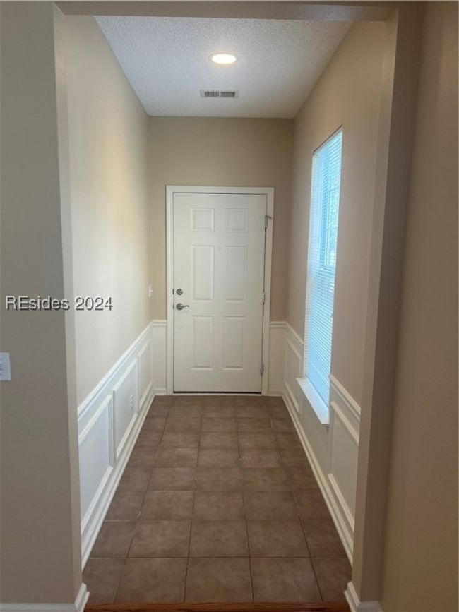 Hall with a textured ceiling and dark tile patterned flooring | Image 8