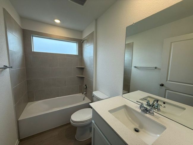 Bathroom featuring toilet, vanity, wood finished floors, and washtub / shower combination | Image 8