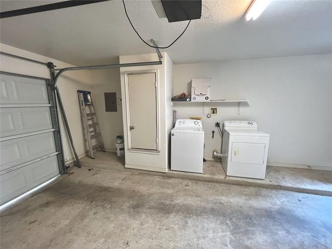 Garage featuring independent washer and dryer, electric panel, and a garage door opener | Image 14