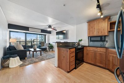 Kitchen with light hardwood / wood-style floors, ceiling fan, black appliances, and dark stone counters | Image 3