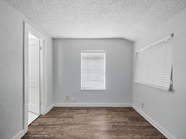 Empty room with a textured wall, dark wood-type flooring, and a textured ceiling | Image 15