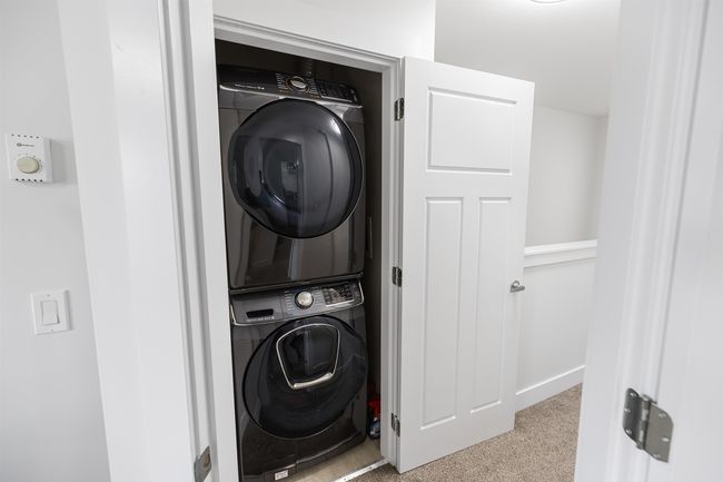 Laundry area featuring estacked washer and dryer and carpet floors | Image 16