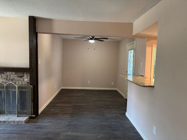Unfurnished living room with a ceiling fan, a brick fireplace, and wood finished floors | Image 4