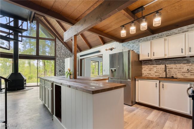 Kitchen featuring butcher block countertops, stainless steel fridge, a sink, wood ceiling with exposed beams, and healthy amount of natural light | Image 10