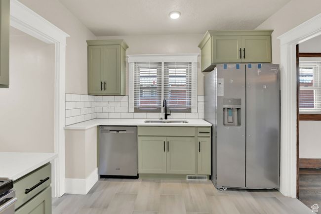 Kitchen featuring green cabinets, stainless steel appliances, a sink, light countertops, and recessed lighting | Image 12