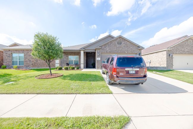 View of front facade with brick siding, driveway, a garage, and a front yard | Image 8