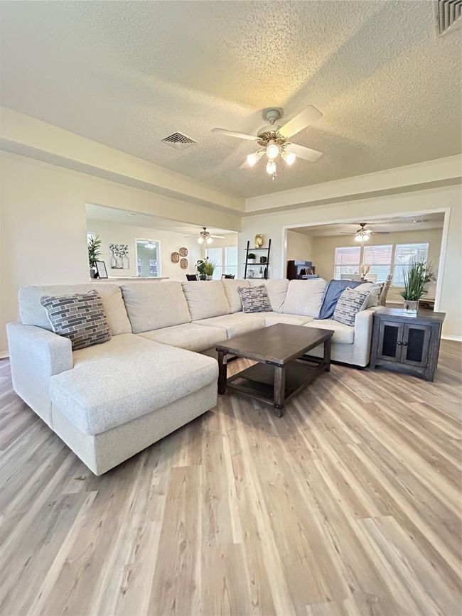 Living room with visible vents, light wood finished floors, and a textured ceiling | Image 5