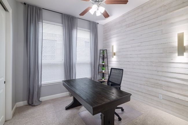 Office space featuring a ceiling fan, light carpet, wooden walls, and baseboards | Image 24