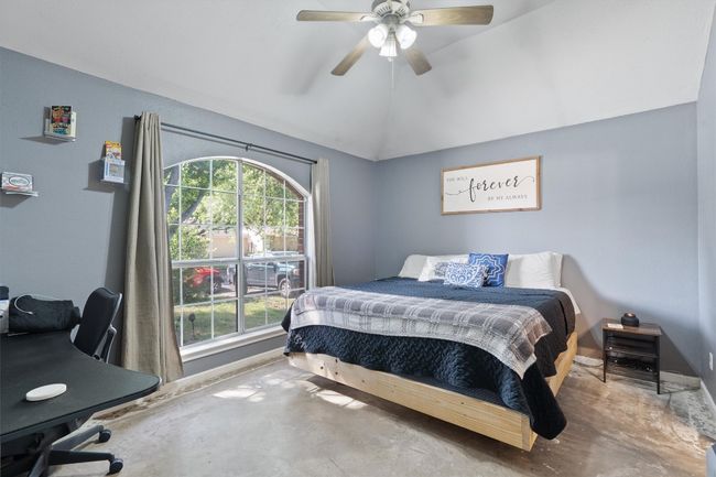 Bedroom featuring unfinished concrete flooring, vaulted ceiling, a ceiling fan, and baseboards | Image 13