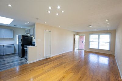 Kitchen/Living Area featuring light hardwood / wood-style flooring, gray cabinets, a skylight, and stainless steel gas range oven | Image 3