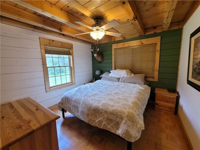 Bedroom featuring dark parquet floors, beamed ceiling, ceiling fan, and wooden ceiling | Image 12