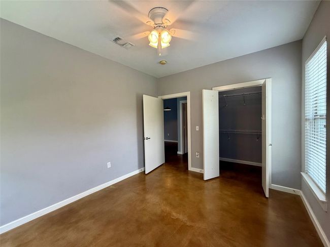 Unfurnished bedroom with baseboards, finished concrete floors, a closet, and ceiling fan | Image 13