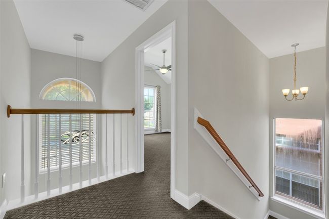 Hall featuring a chandelier, an upstairs landing, dark carpet, and lofted ceiling | Image 18