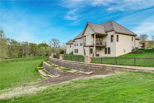 Rear view of house with a fenced backyard, a balcony, a yard, central air condition unit, and stucco siding | Image 60