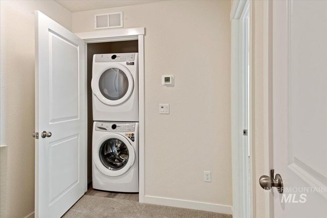Washroom featuring stacked washer / drying machine and a textured wall | Image 16