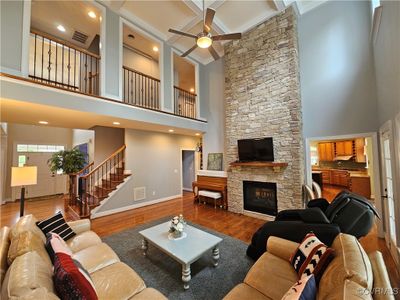 Living room with ceiling fan, a towering ceiling, hardwood / wood-style floors, and a fireplace | Image 3