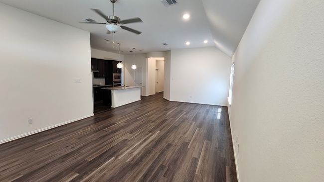 Unfurnished living room with ceiling fan, dark wood finished floors, baseboards, recessed lighting, and lofted ceiling | Image 9