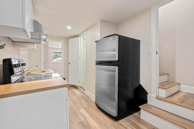 Kitchen featuring freestanding refrigerator, light wood finished floors, white cabinetry, and a sink | Image 13