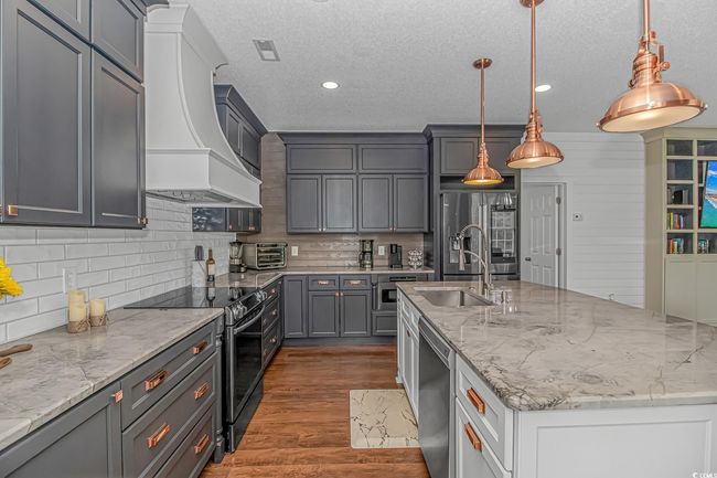 Kitchen featuring appliances with stainless steel finishes, premium range hood, a sink, a textured ceiling, and tasteful backsplash | Image 12