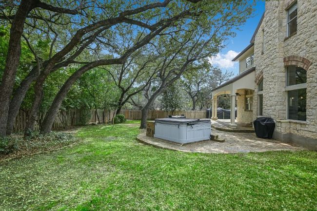View of yard with a hot tub, a fenced backyard, ceiling fan, and a patio. | Image 35