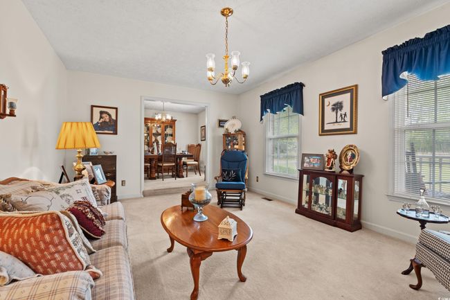 Living room with baseboards, carpet floors, and a notable chandelier | Image 8