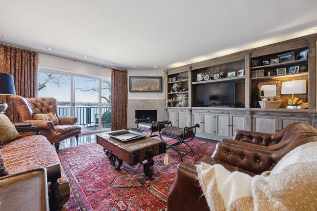 Spacious living area with lake views, balcony overlooking the lake and a fireplace. | Image 16