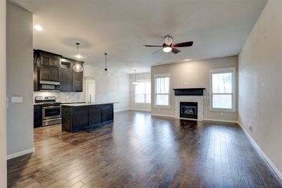 Kitchen featuring gas range, dark hardwood / wood-style flooring, an island with sink, and a fireplace | Image 3