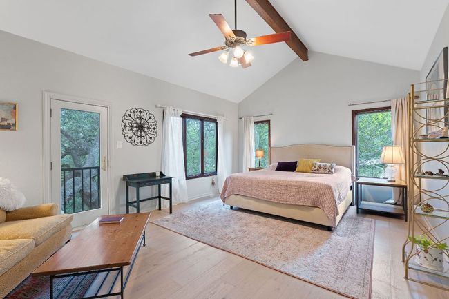 Bedroom featuring wood finished floors, beam ceiling, high vaulted ceiling, access to outside, and ceiling fan | Image 17