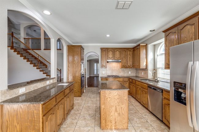 Kitchen with a center island, arched walkways, stainless steel appliances, under cabinet range hood, and visible vents | Image 8