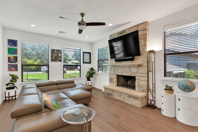 Living room featuring ceiling fan, wood finished floors, a stone fireplace, and recessed lighting | Image 10