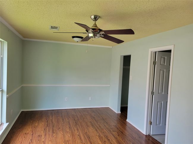 Empty room featuring a ceiling fan, wood finished floors, a textured ceiling, and ornamental molding | Image 25