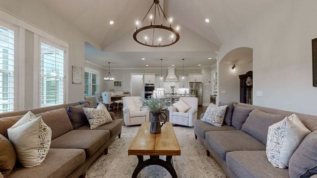 Spacious, bright, and beautifully designed—this open living area features vaulted ceilings, custom lighting, and plenty of room to relax or gather, all flowing effortlessly into the kitchen and dining spaces. | Image 22