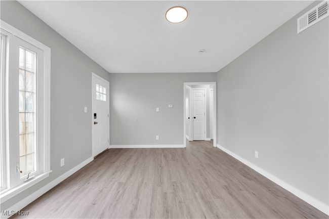 Unfurnished living room featuring baseboards, visible vents, a wealth of natural light, and light wood finished floors | Image 4
