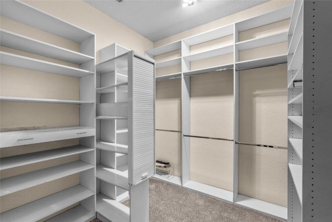 Primary walking closet with custom shelving including ironing board | Image 37