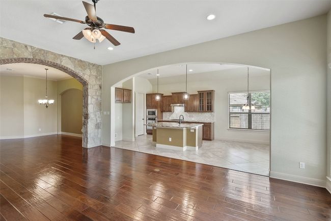 Unfurnished living room with a chandelier, light wood-style floors, arched walkways, a ceiling fan, and recessed lighting | Image 15