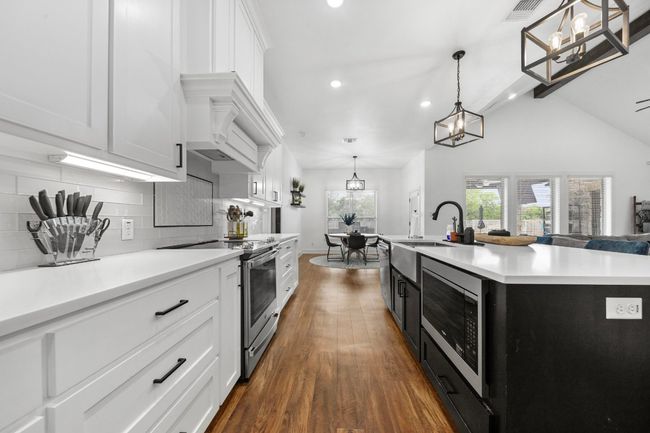 Kitchen with an inviting chandelier, dark wood-style floors, light countertops, stainless steel appliances, and a sink | Image 6