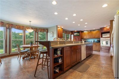 Kitchen with white appliances, a kitchen breakfast bar, an island with sink, and sink | Image 3