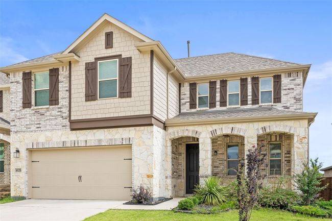 View of property with stone siding, a garage, concrete driveway, covered porch, and roof with shingles | Image 39